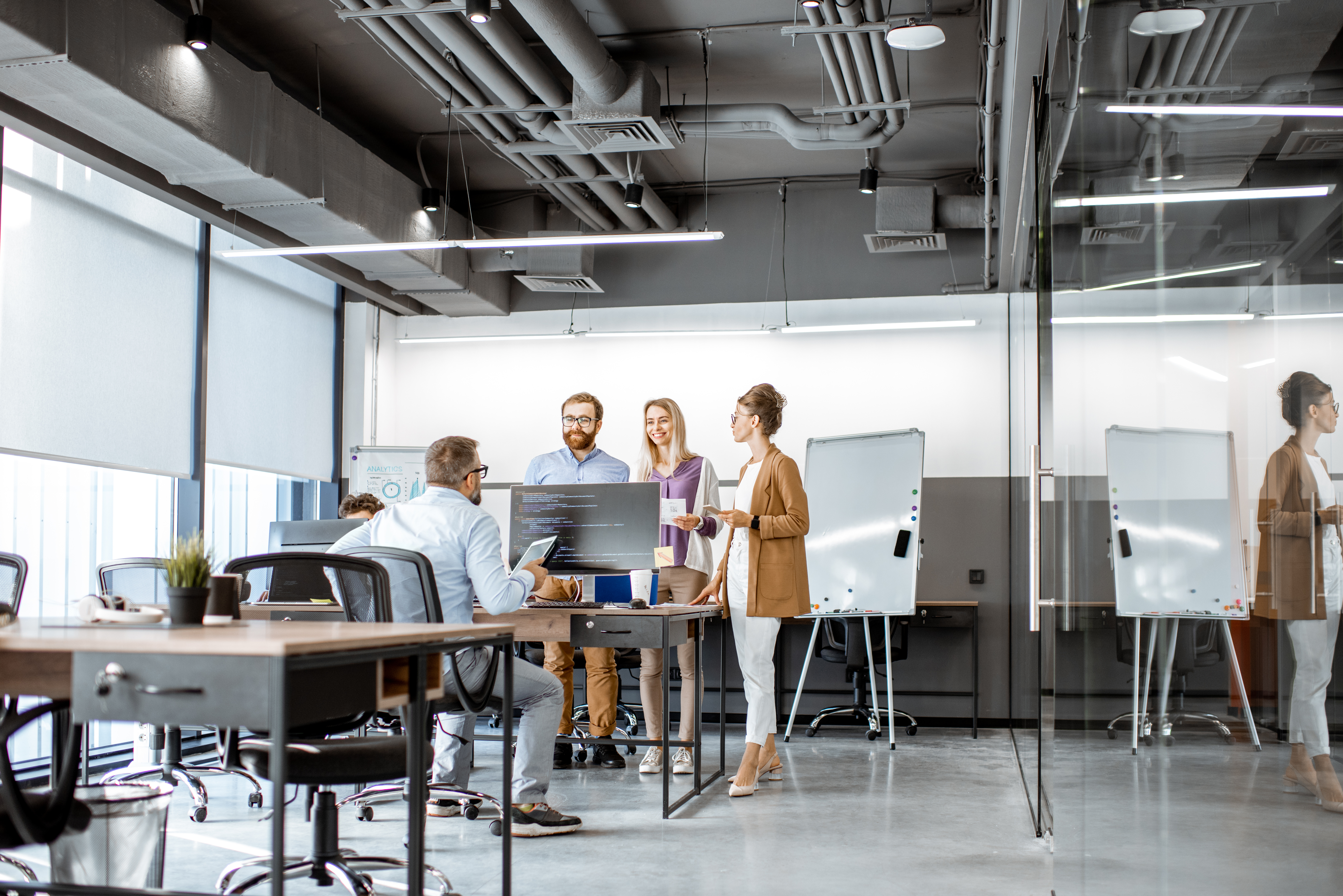 Zwei Kolleginnen und zwei Kollegen unterhalten sich in einem Büro