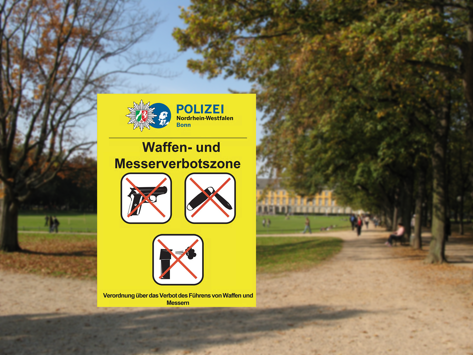 Der Bonner Hofgarten. Im Vordergrund ein Symbolschild der Waffen- und Messerverbotszone mit Piktogrammen der verbotenen Gegenstände