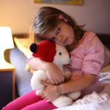 Bild eines traurigen Kindes mit Teddybär im Arm
