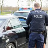 Bild einer Kontrollaktion durch die Polizei. Ein Beamter kontrolliert Ausweispapiere