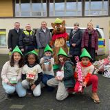 Die Geschenkübergabe bei Robin Good mit Botschafterkindern vor Polizeiauto. Weihnachtsgeschenke rechts im Bild.