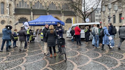 Der Infostand der Bonner Polizei mit vielen Menschen sowie einer Radfahrerin im Vordergrund